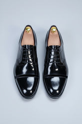 Black patent leather dress shoes with lace-up design and classic style.